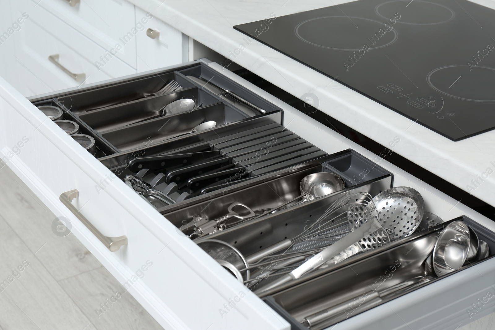 Photo of Open drawer with stainless steel utensil set, closeup. Order in kitchen