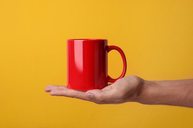 Photo of Man holding red mug on yellow background, closeup