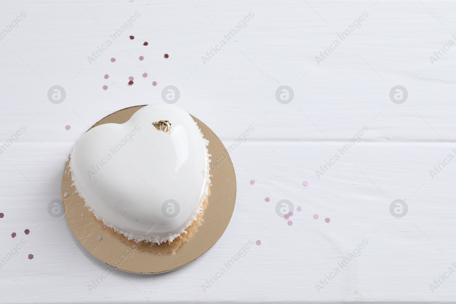 Photo of St. Valentine's Day. Delicious heart shaped cake and confetti on white wooden table, top view. Space for text