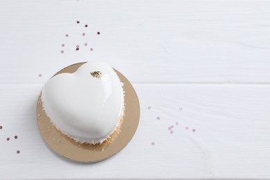 St. Valentine's Day. Delicious heart shaped cake and confetti on white wooden table, top view. Space for text