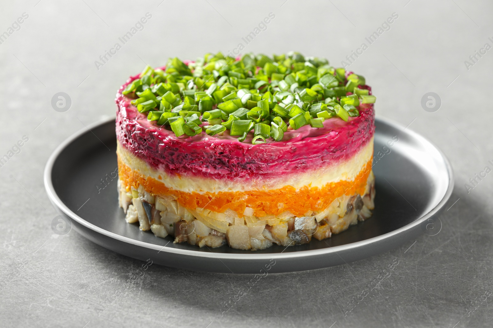 Photo of Herring under fur coat salad on grey table, closeup. Traditional Russian dish