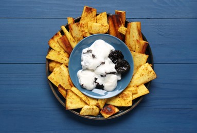 Photo of Delicious parsnips and prunes in cream sauce on blue wooden table, top view