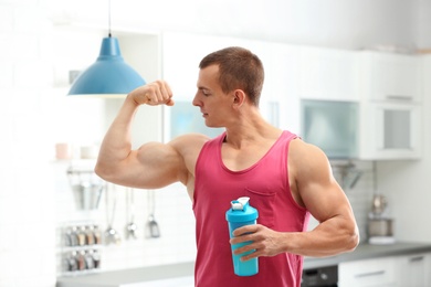 Photo of Athletic young man with protein shake in kitchen