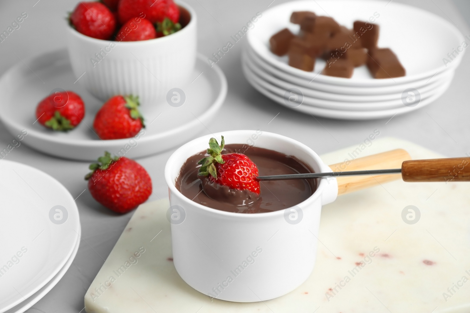 Photo of Fondue pot with chocolate and strawberry on grey table