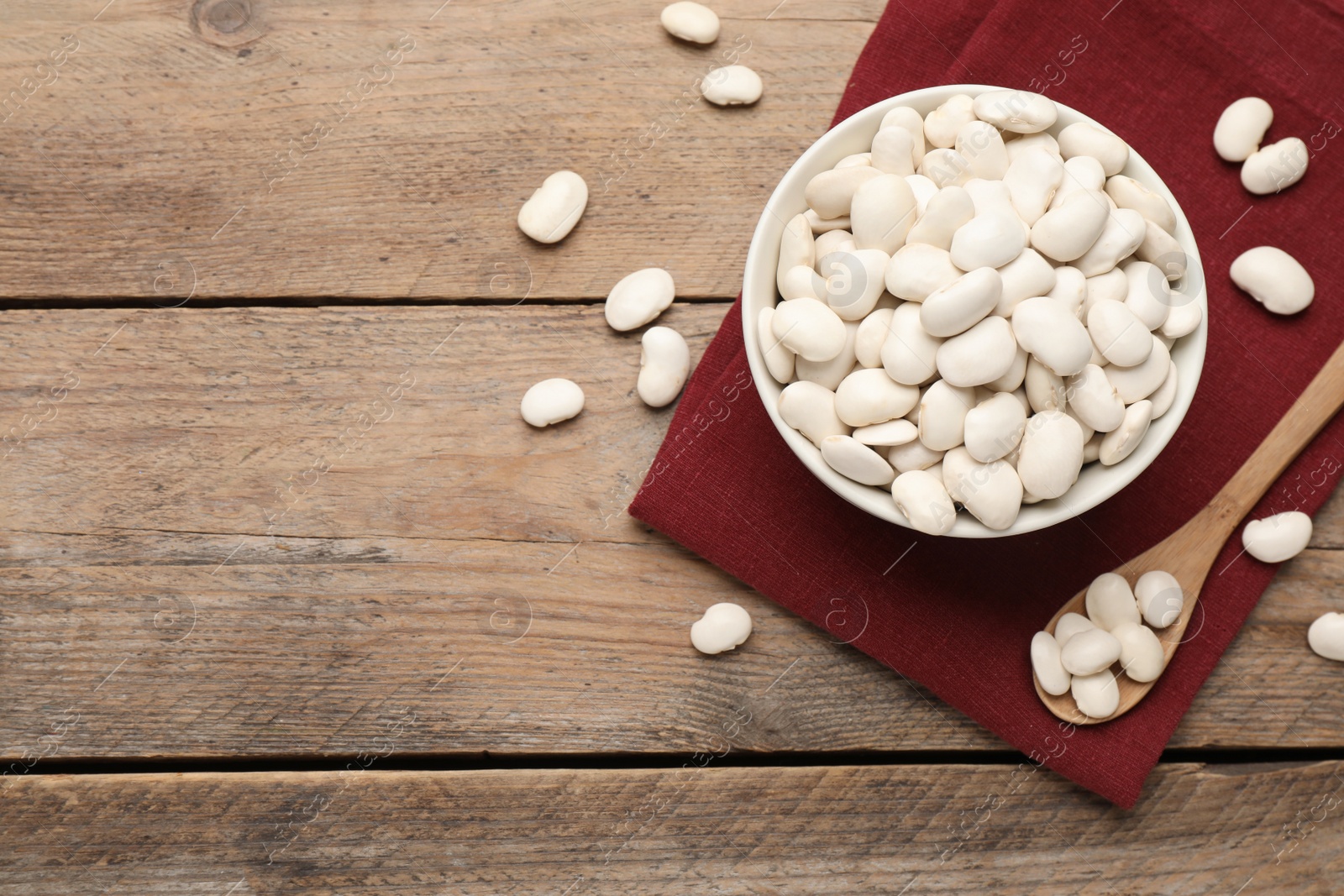 Photo of Raw white beans on wooden table, flat lay. Space for text