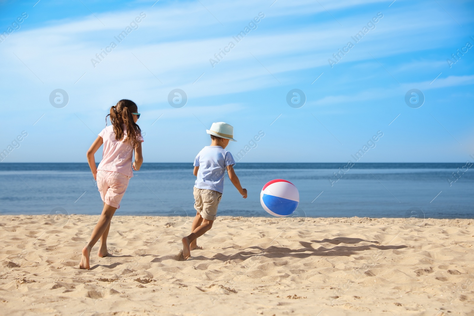 Photo of Cute little children playing with inflatable ball on sandy beach