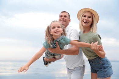 Happy family spending time together near sea on sunny summer day