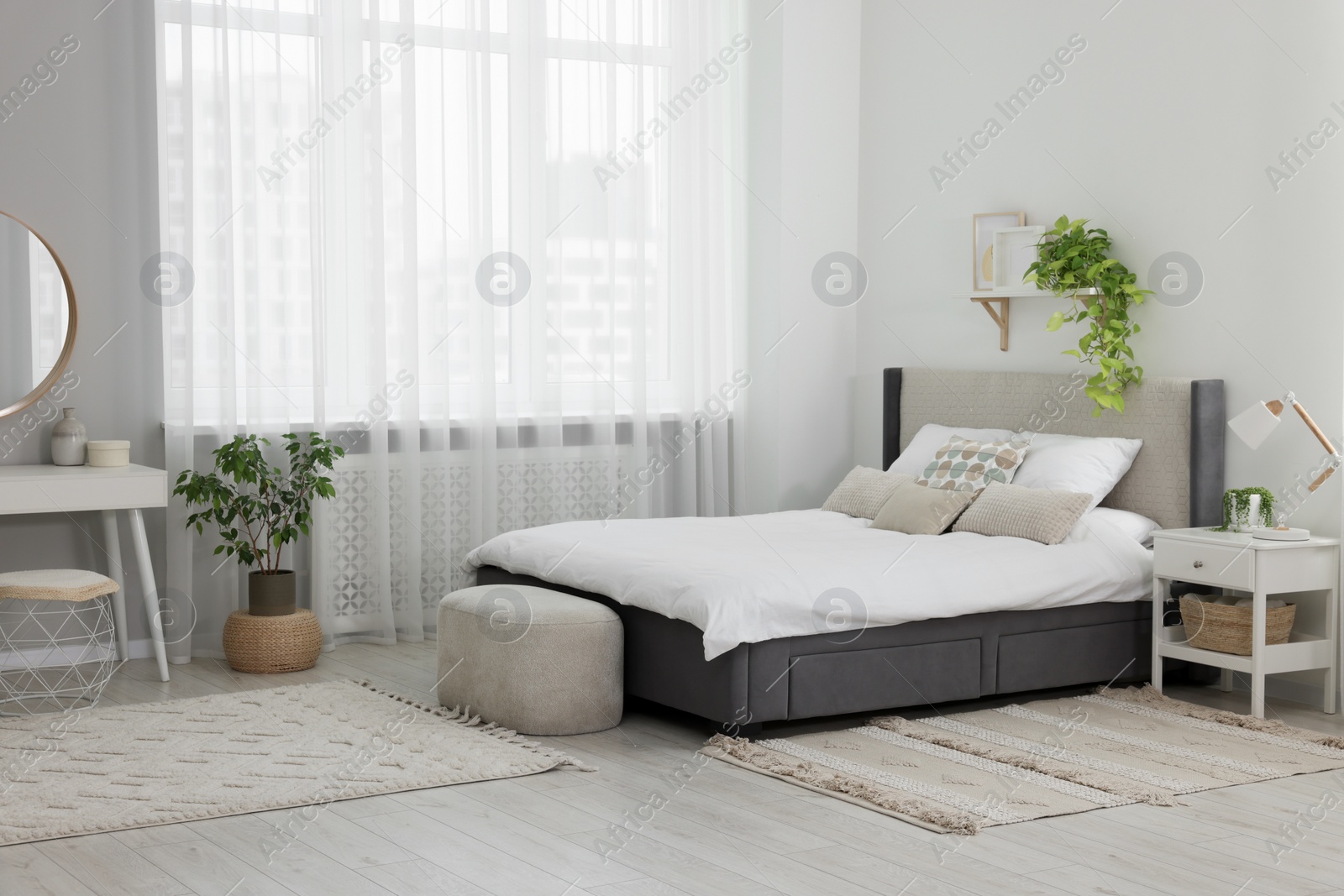 Photo of Stylish bedroom interior with large comfortable bed and ottoman near window