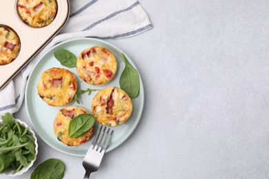 Freshly baked bacon and egg muffins with cheese on light gray table, flat lay. Space for text