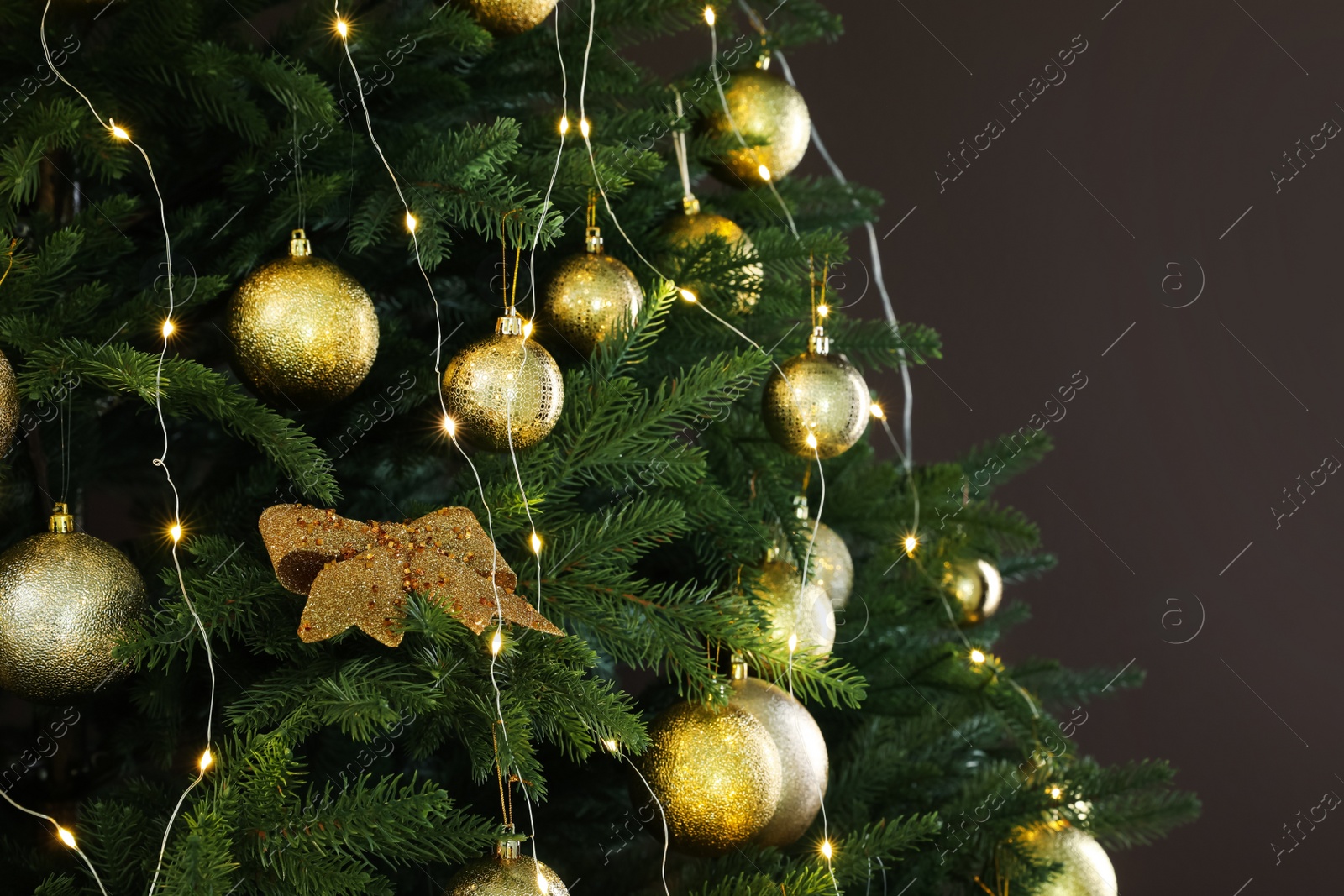 Photo of Beautifully decorated Christmas tree on brown background, closeup