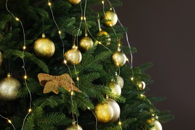 Photo of Beautifully decorated Christmas tree on brown background, closeup