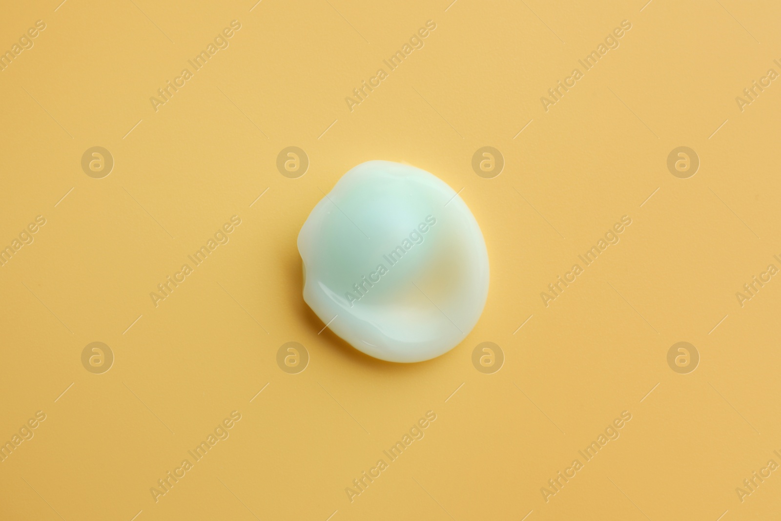 Photo of Sample of face cream on yellow background, top view