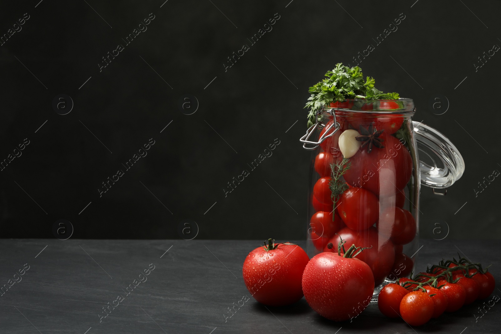Photo of Pickling jar with fresh ripe cherry tomatoes on black table. Space for text
