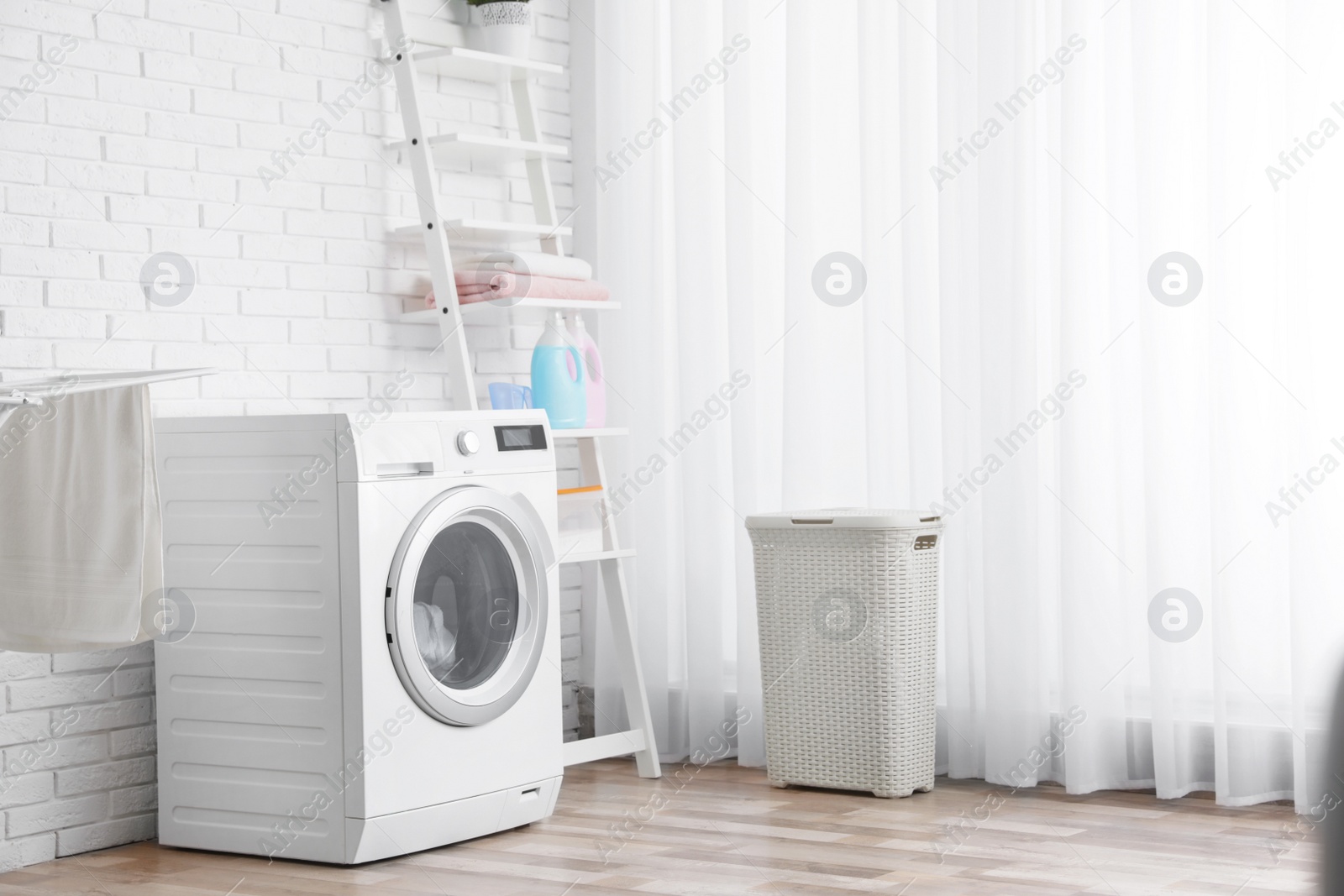 Photo of Modern washing machine near brick wall in laundry room interior, space for text