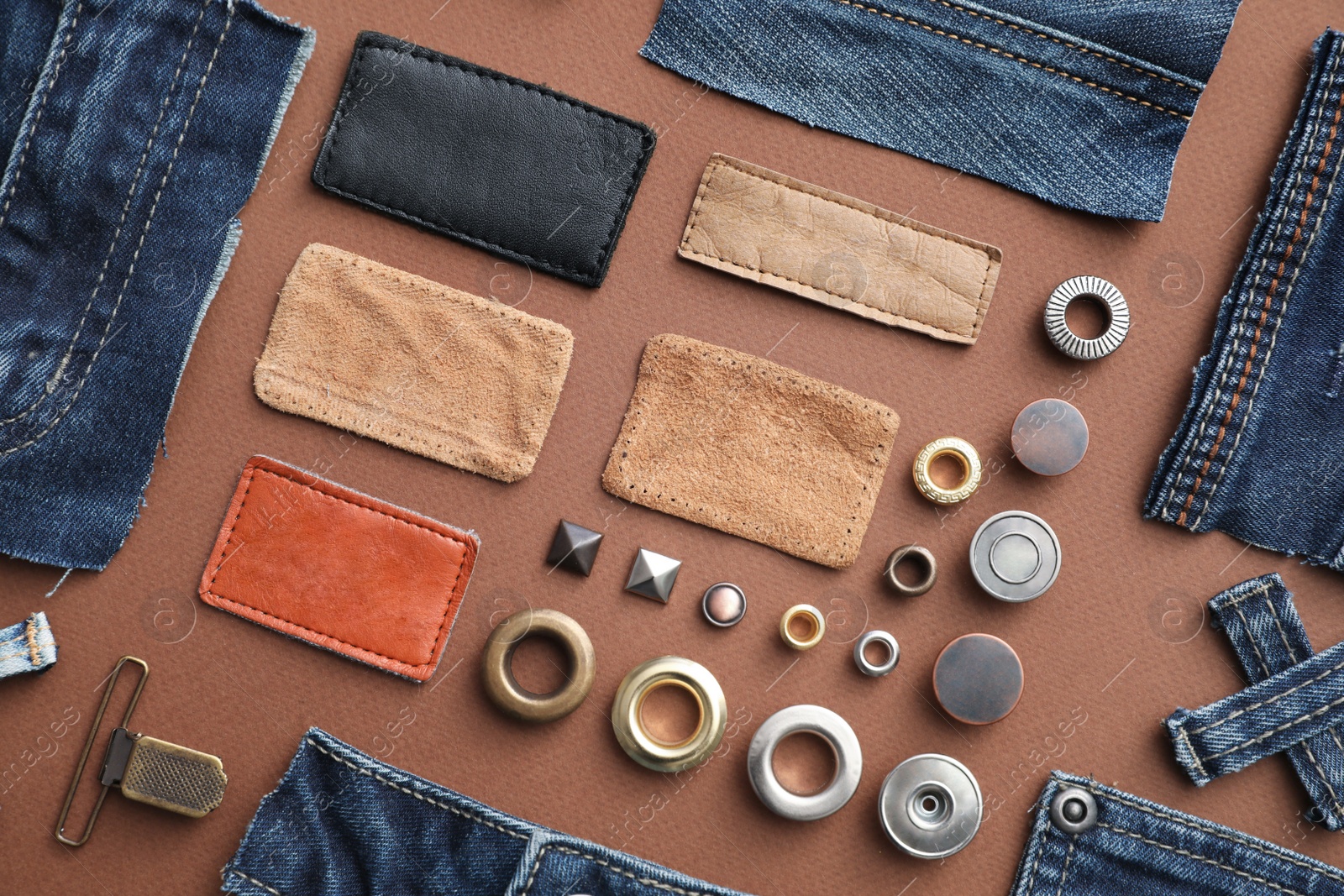 Photo of Flat lay composition with garment accessories and cutting details for jeans on brown background