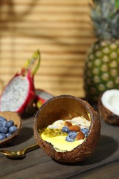 Tasty smoothie bowl with fresh blueberries and almonds served in coconut shell on wooden table