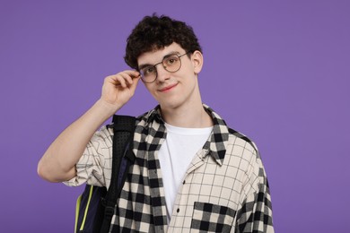 Portrait of student with backpack on purple background