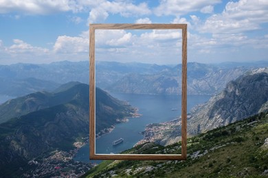Image of Wooden frame and beautiful bay between mountains under blue sky with clouds