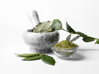 Photo of Mortar and pestle with bay leaves on white background