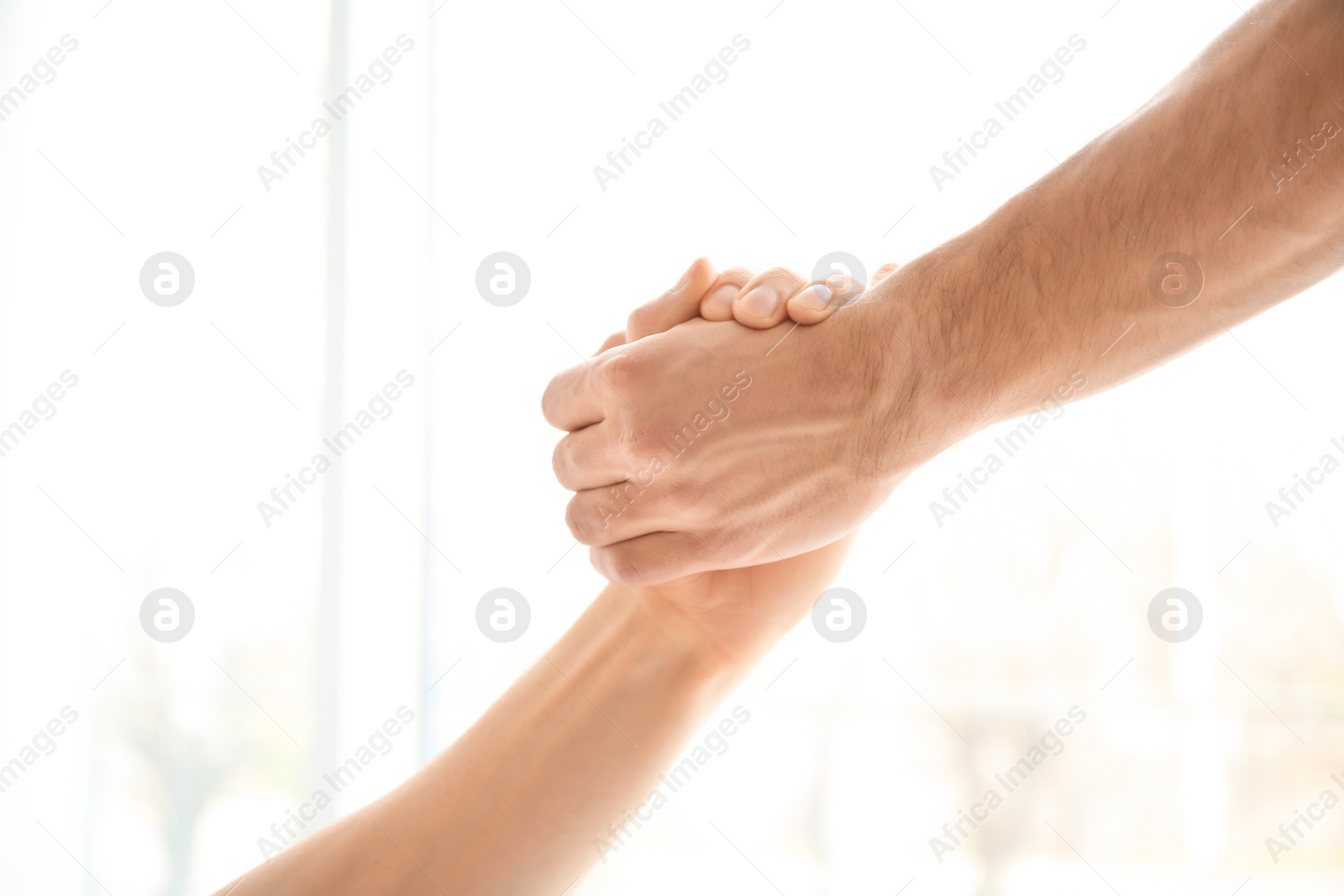 Photo of Man and woman holding hands together on light background. Unity concept