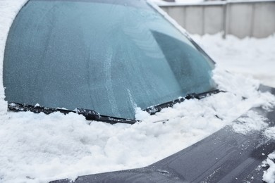 Car windshield with wiper blades cleaned from snow outdoors on winter day