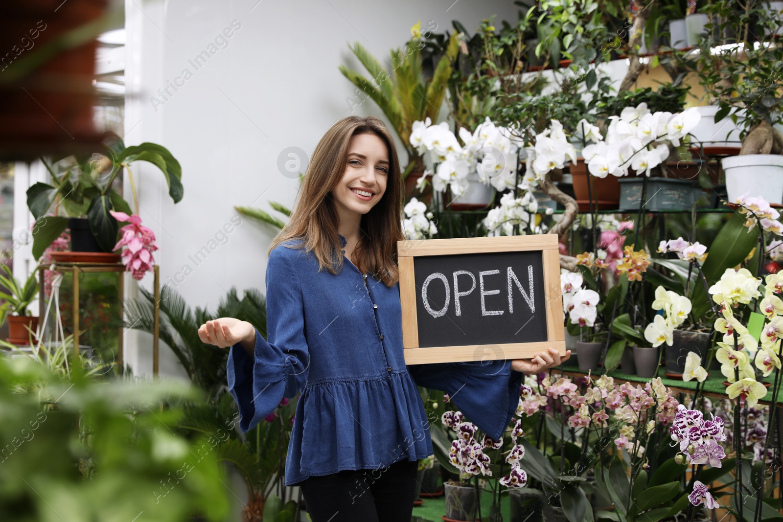 Photo of Young business owner holding OPEN sign in flower shop