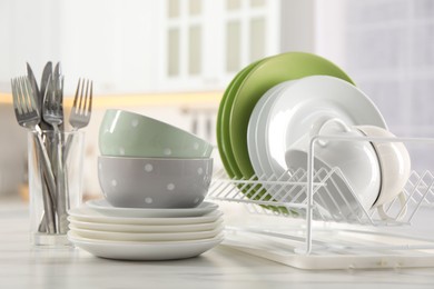 Photo of Many different clean dishware, cups and cutlery on white marble table in kitchen