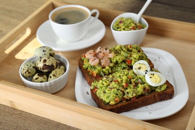 Photo of Slices of bread with tasty guacamole, eggs, shrimp and coffee on wooden table