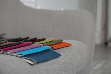 Catalog of colorful fabric samples on grey sofa indoors, closeup. Space for text