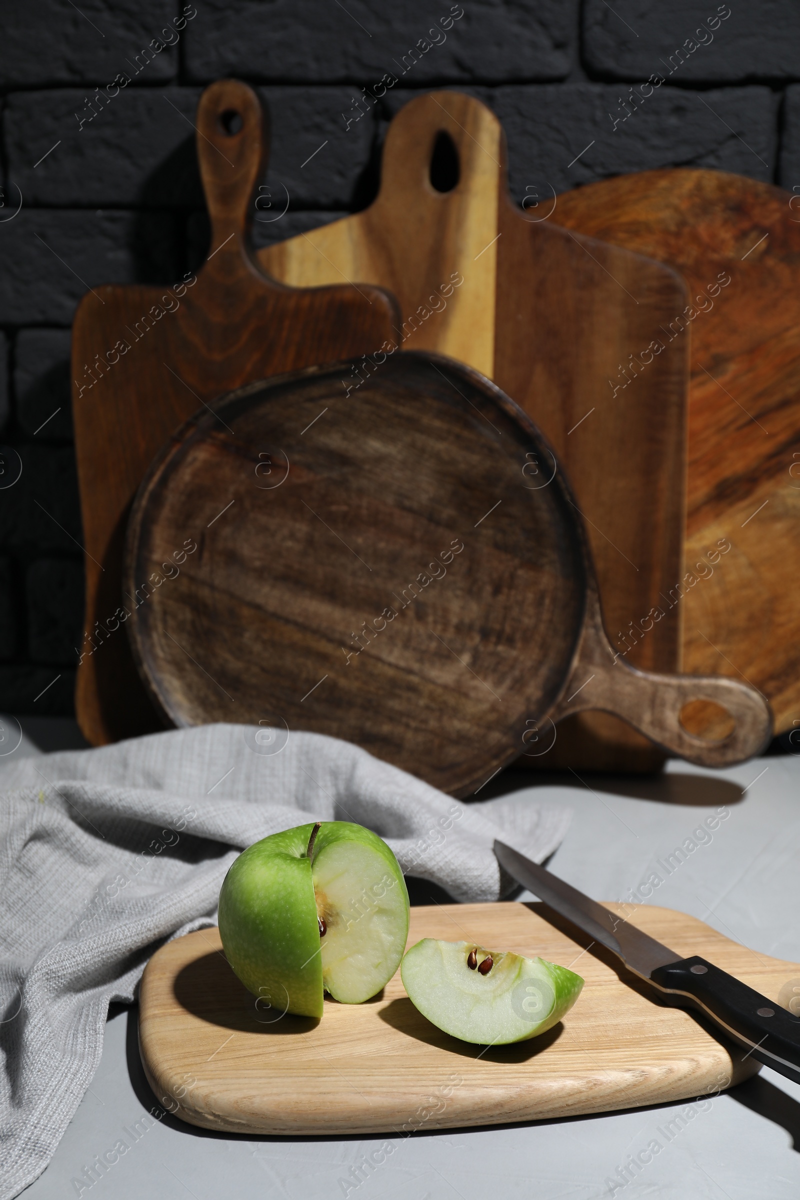 Photo of Wooden cutting boards, cut apple and knife on gray table