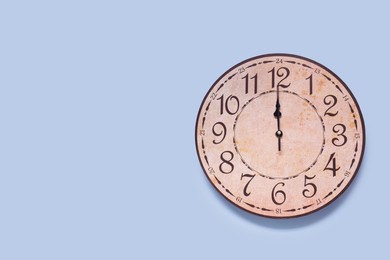 Photo of Stylish round clock on light blue background, top view with space for text. Interior element