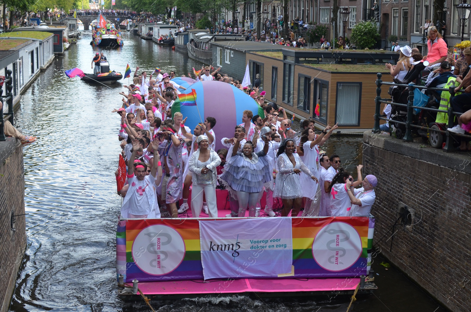 Photo of AMSTERDAM, NETHERLANDS - AUGUST 06, 2022: Many people in boats at LGBT pride parade on river