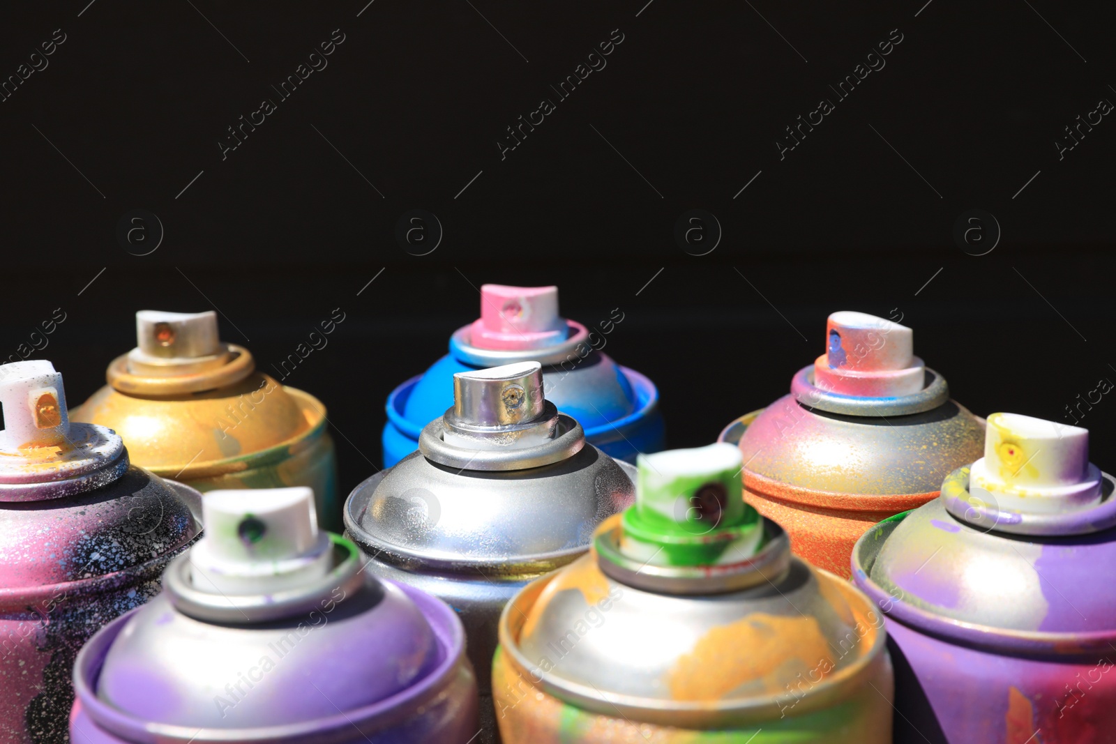Photo of Used cans of spray paint on dark background, closeup. Graffiti supplies