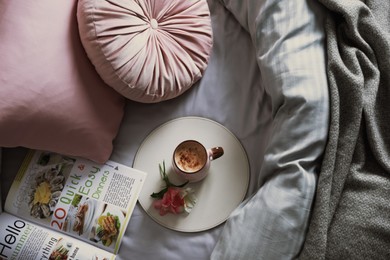 Aromatic coffee, magazine and beautiful flowers on bed with fresh linens, top view