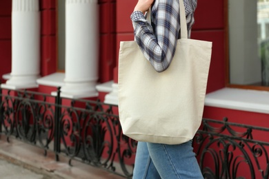 Photo of Young woman with cotton bag on city street, closeup. Mockup for design