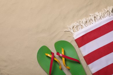 Photo of Beach towel and flip flops on sand, flat lay. Space for text