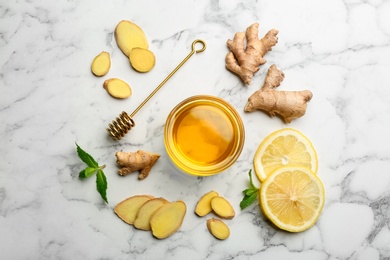 Photo of Ginger and other natural cold remedies on white marble table, flat lay