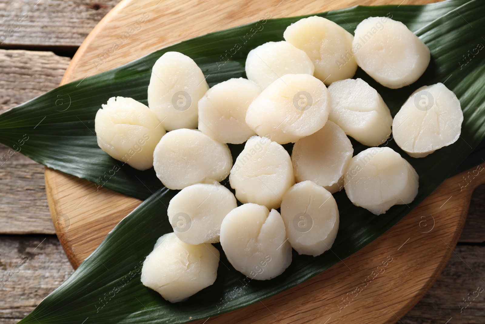 Photo of Fresh raw scallops on wooden table, top view