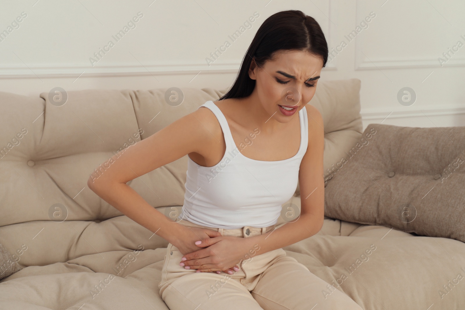 Photo of Woman suffering from appendicitis inflammation on sofa indoors