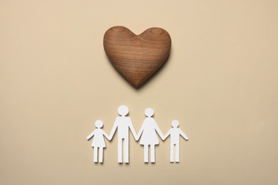 Photo of Paper family figures and wooden heart on beige background, flat lay. Insurance concept