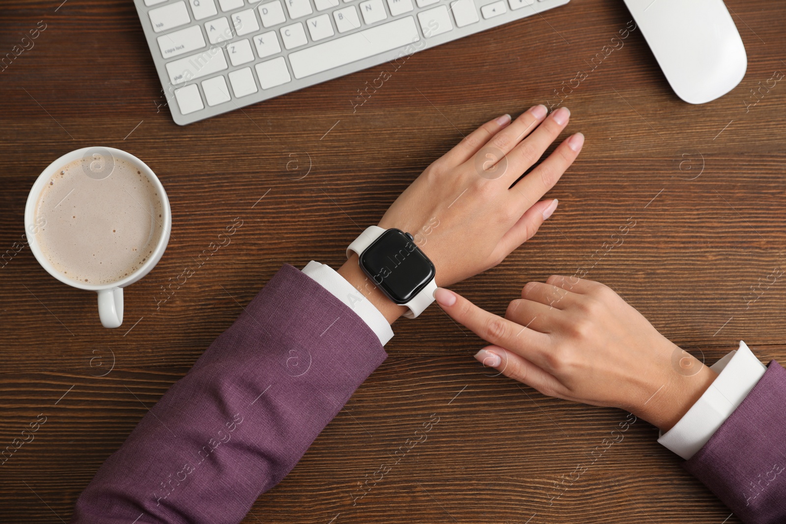 Image of Woman using stylish smart watch at wooden table, top view