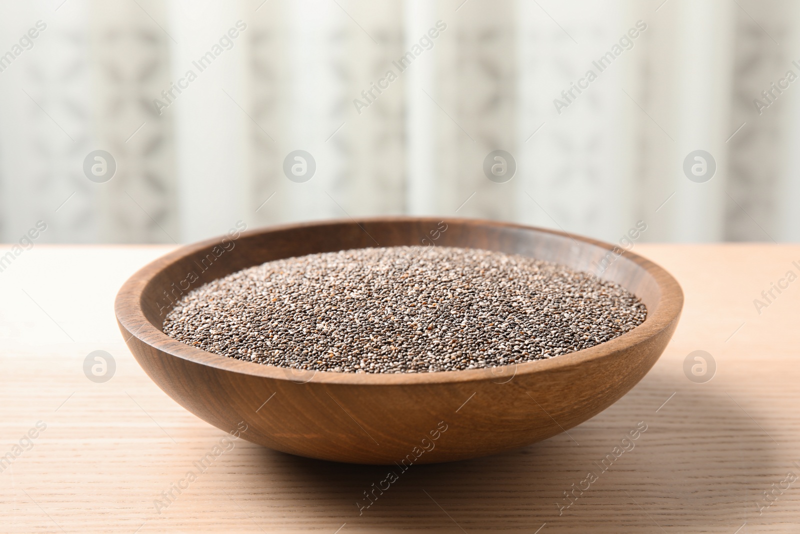 Photo of Bowl with chia seeds on table against blurred background