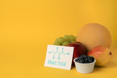Photo of Card with word Fructose, delicious ripe fruits and blueberries on yellow background, space for text