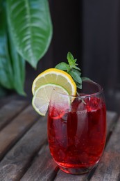 Photo of Glass of delicious cocktail with lemon and lime slices on wooden table. Refreshing drink