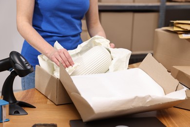 Post office worker packing parcel at wooden table indoors, closeup