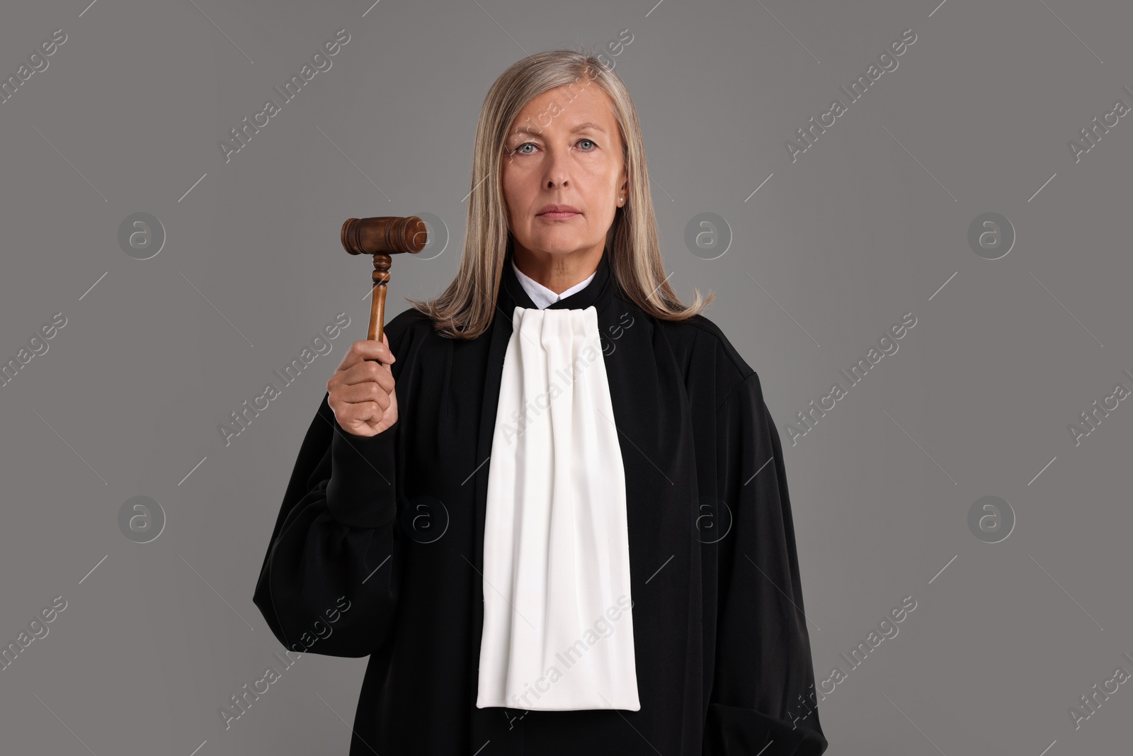 Photo of Senior judge with gavel on grey background