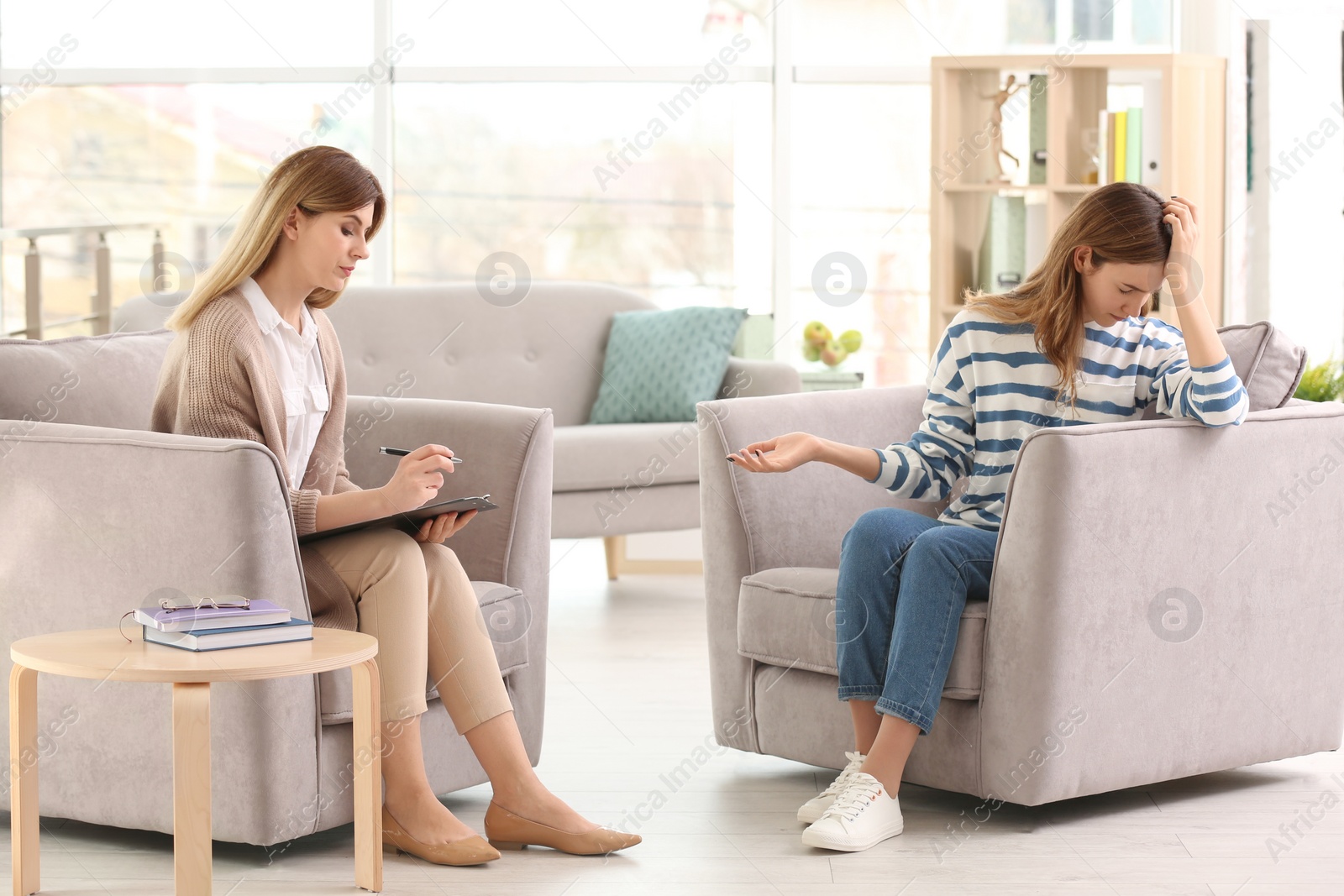 Photo of Young female psychologist working with teenage girl in office