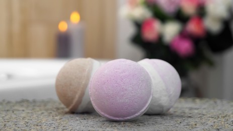 Photo of Colorful bath bombs on wicker mat in bathroom, closeup