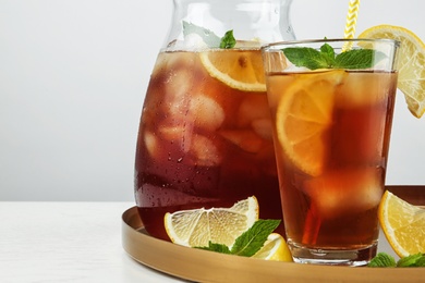 Photo of Jug and glass of delicious iced tea on table