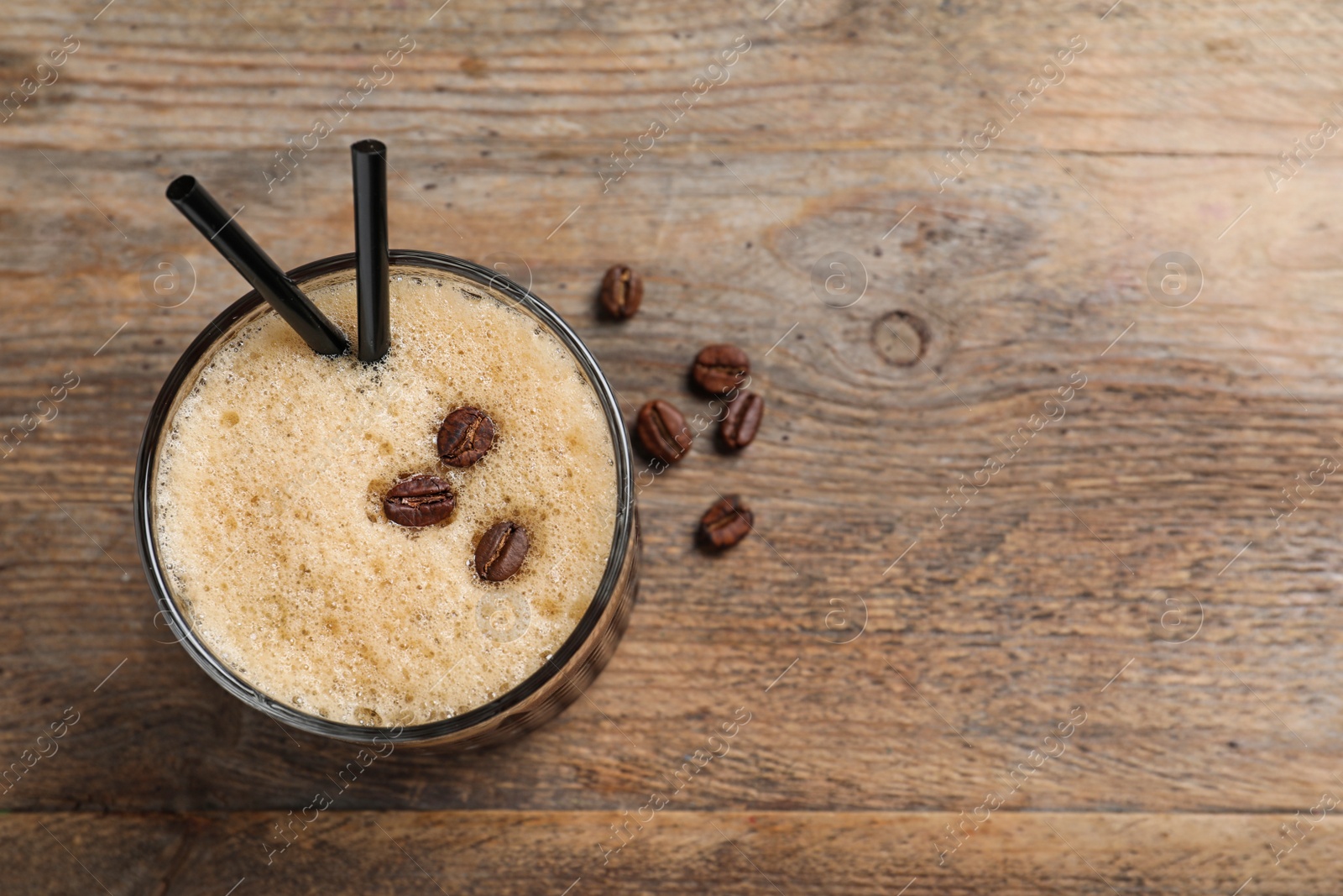 Photo of Glass of tasty refreshing cocktail with coffee beans on wooden background, top view. Space for text